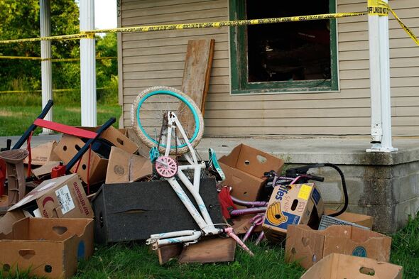 Police tape surrounds a home and debris is seen on the front lawn, where authorities say they removed 16 children and arrested f