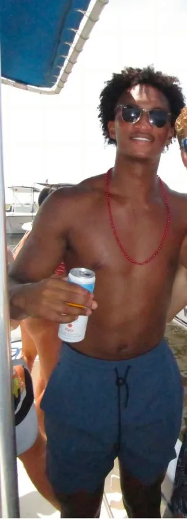 Nolan Wells on a boat, wearing sunglᴀsses and holding a can, while looking at the camera.