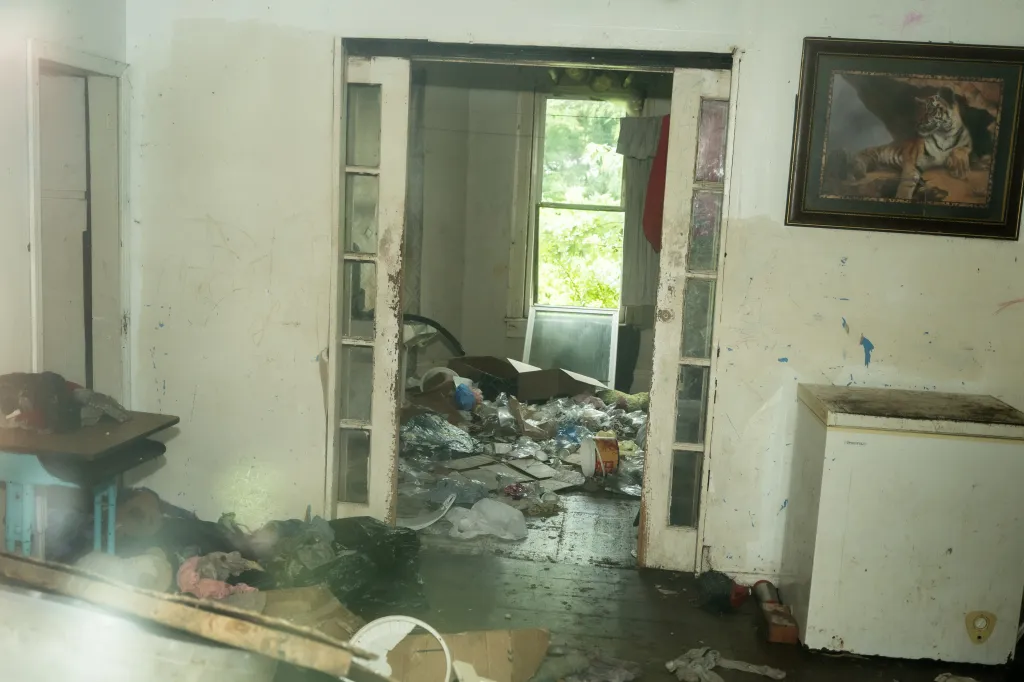 Interior view of the Siders' home showing a room filled with trash and a dirty chest freezer.