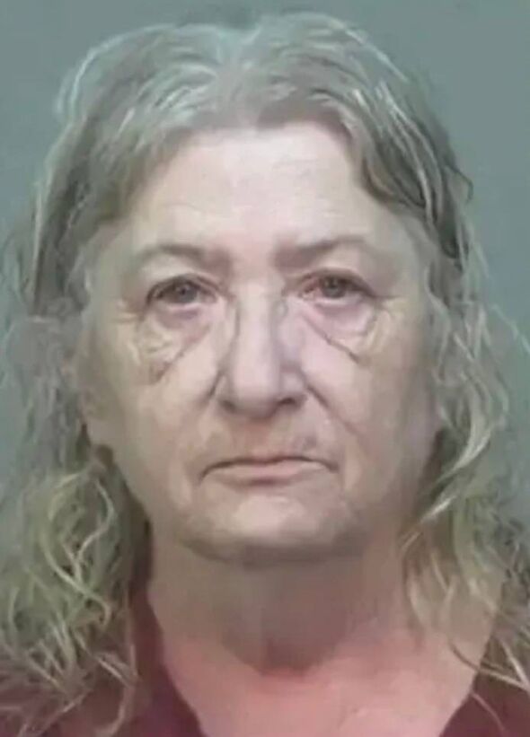 An individual with graying hair and a serious expression, captured in a close-up mugshot. The person appears to be an older woma