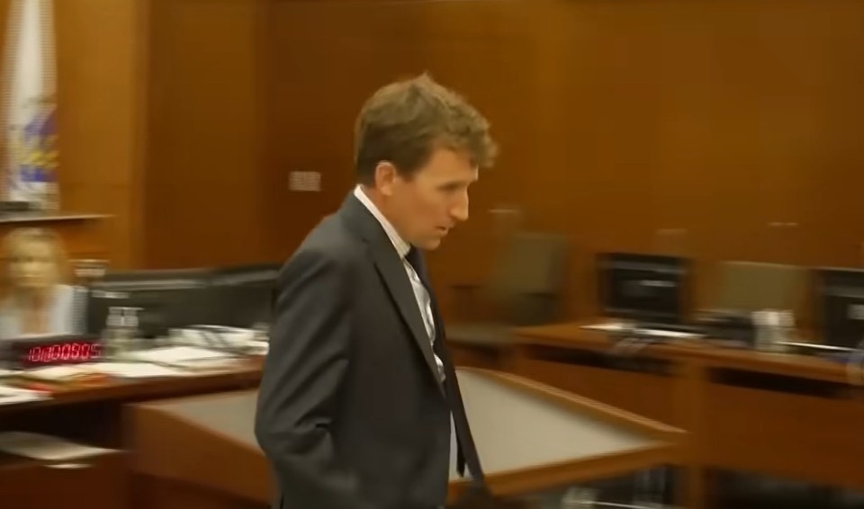 A man in a suit walking in a courtroom.