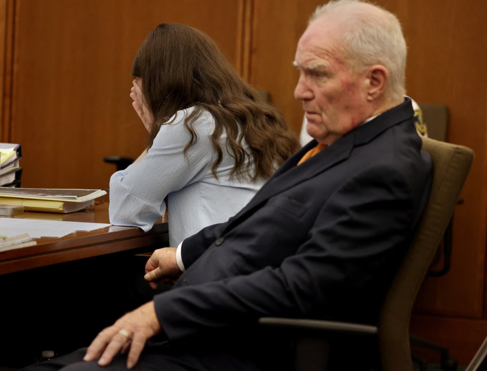 Lindsay Clancy covers her face in court while her defense attorney, Kevin Reddington, sits beside her.