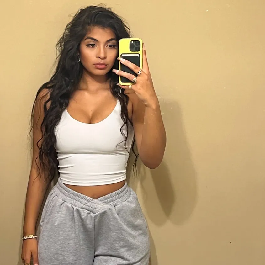 Brittany Boltinhouse, ex-Miss North Carolina USA, holds a yellow phone and wears a white top and gray sweatpants in mirror selfie