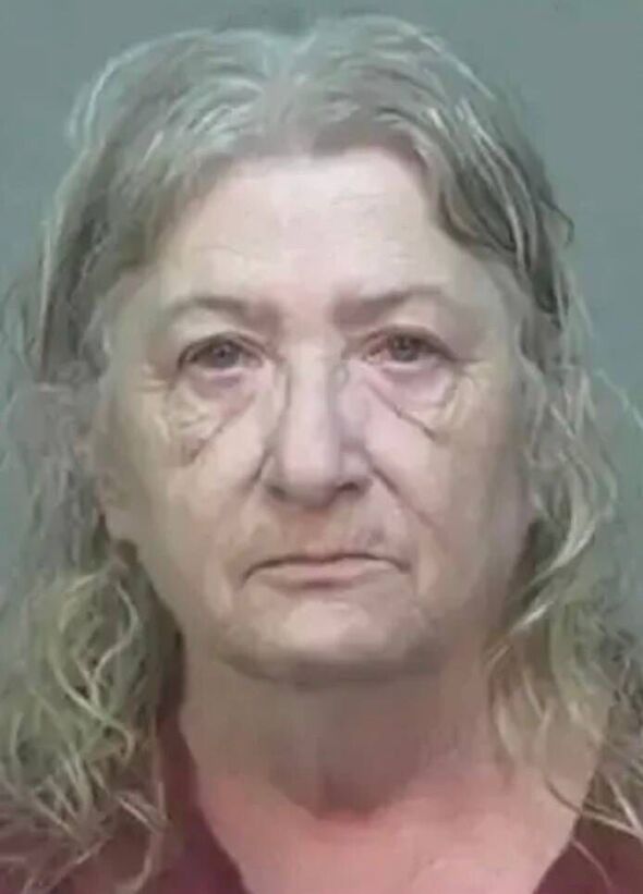 An individual with graying hair and a serious expression, captured in a close-up mugshot. The person appears to be an older woma