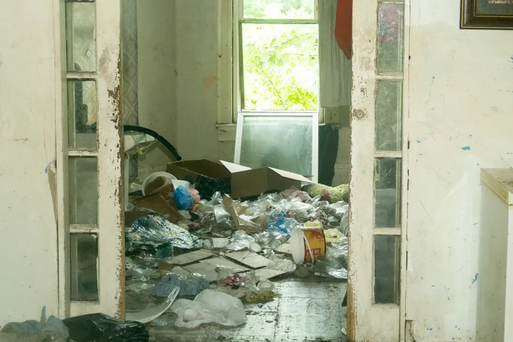 Interior view of a neglected room at the Sider's home, filled with trash and debris.
