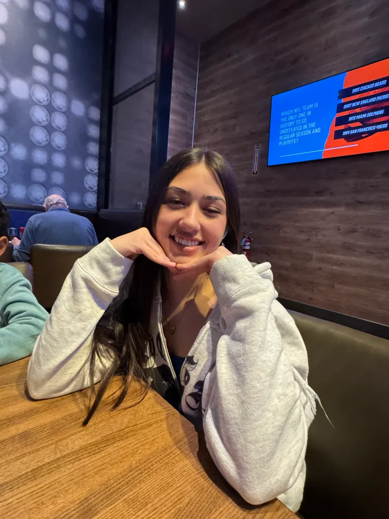 Sophia Cover smiling while sitting at a table in a restaurant.