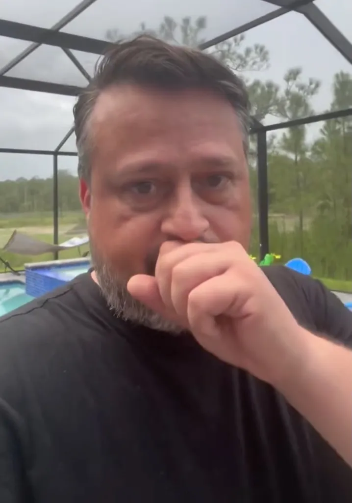 Man covering his mouth with his hand, looking confused or concerned.