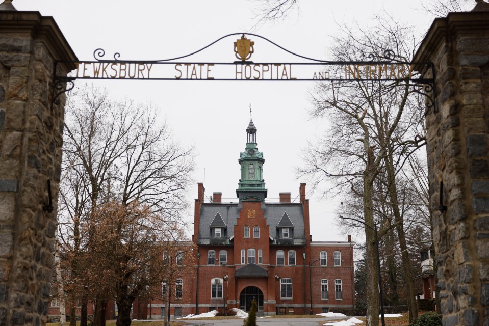 The exterior of Tewksbury State Hospital, framed by a decorative archway, on a cloudy day in January.