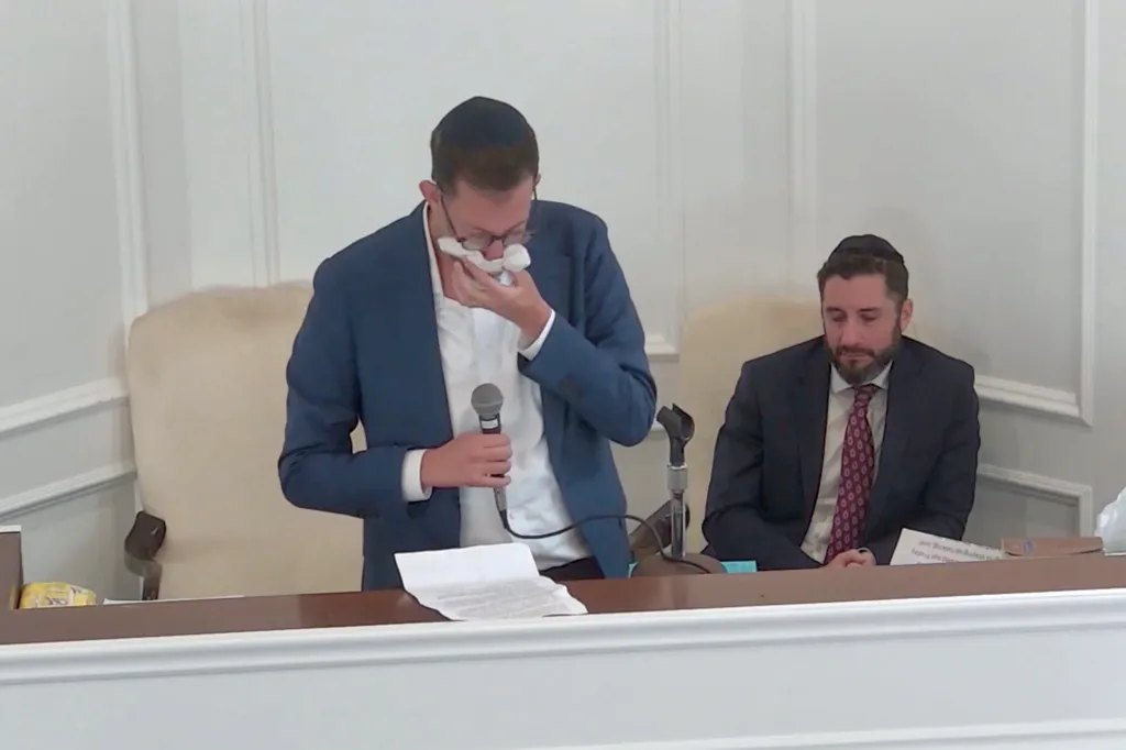 Matthew Rahmani crying into a tissue while speaking at a service.