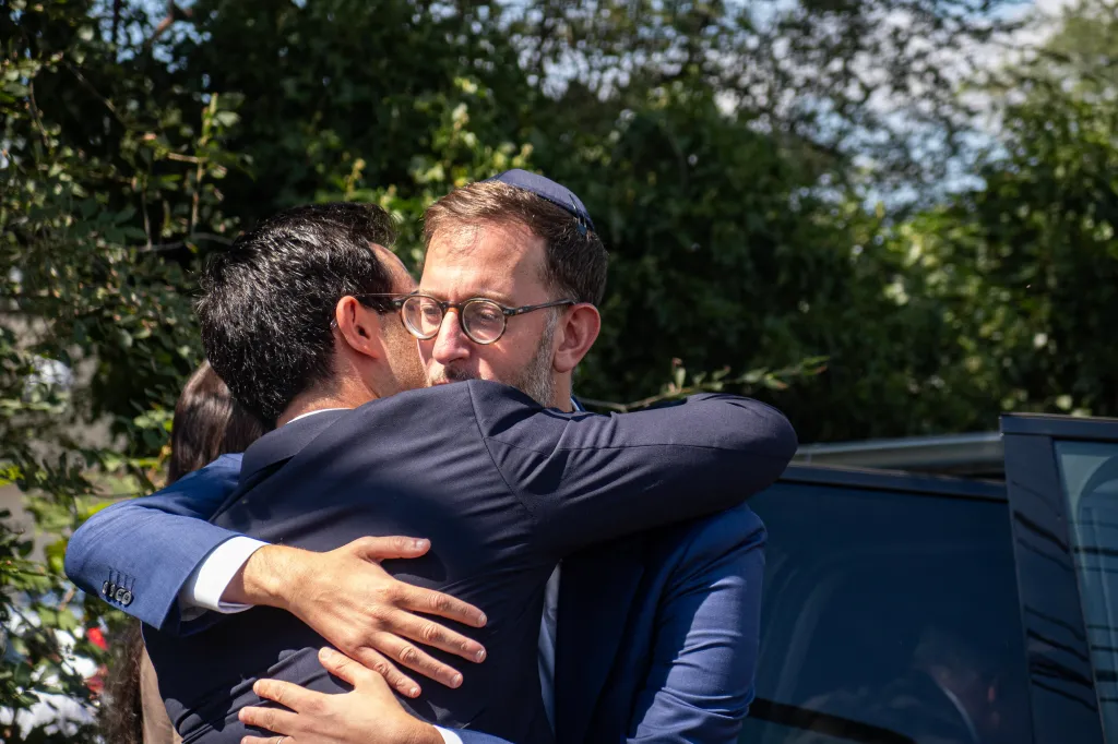 Matthew Rahmani embraces a mourner at his wife's funeral.