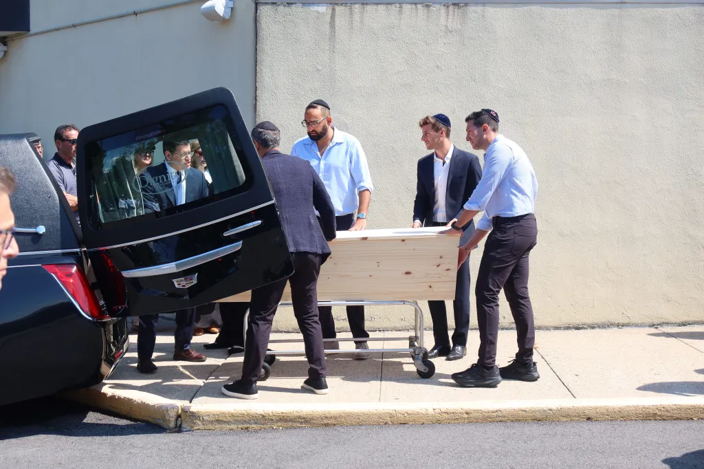 Mourners prepare to load a casket into a hearse.