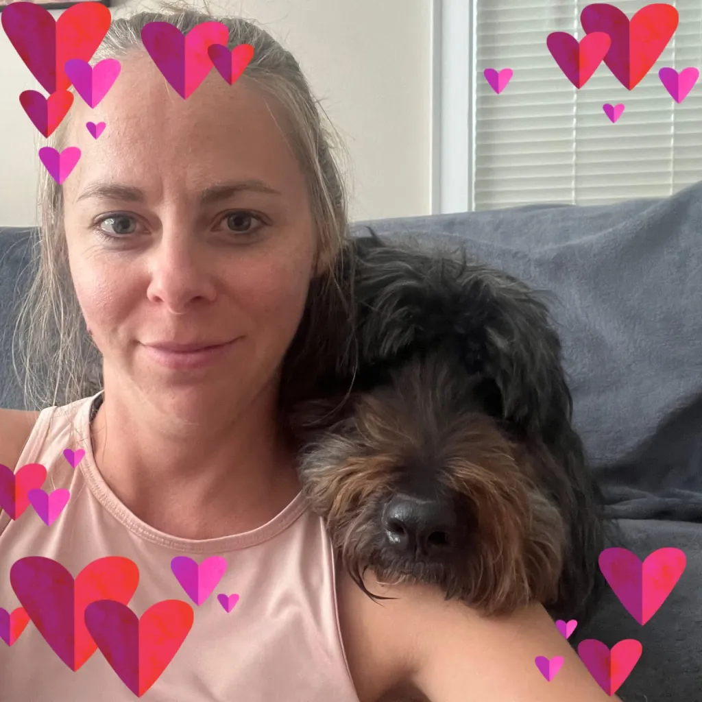 Lindsey Barnett smiling with a dark-haired dog resting its head on her shoulder.