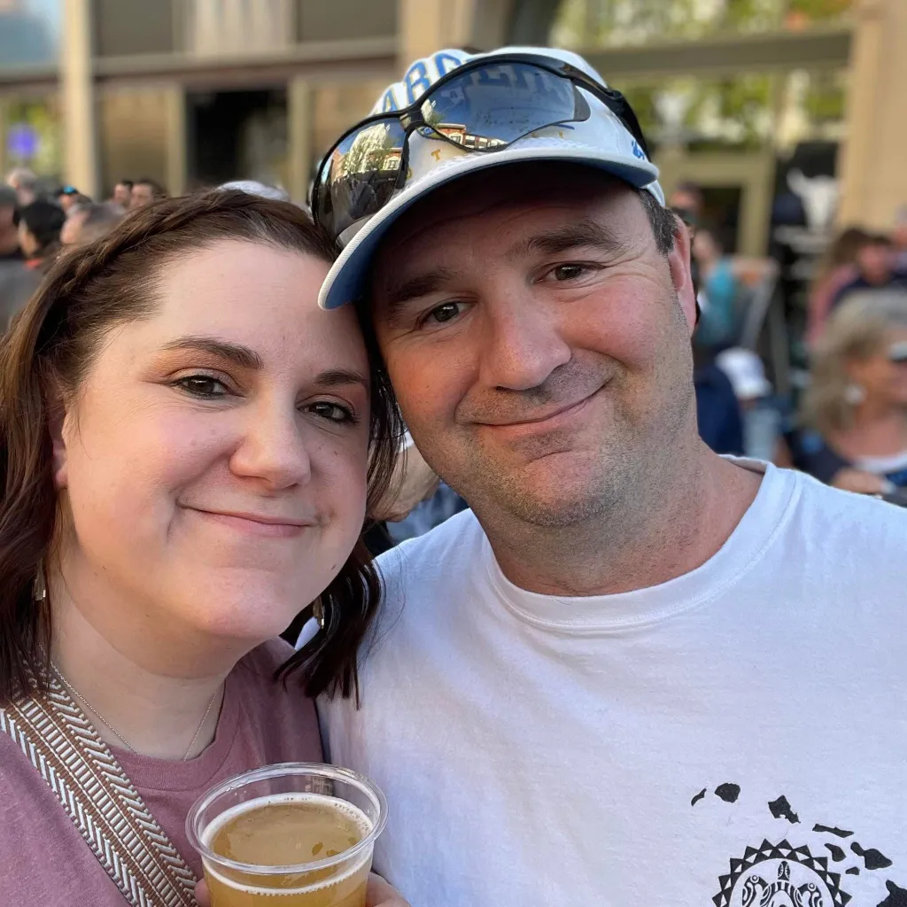 Megan and Adam Ghekiere smiling, with Megan holding a drink.