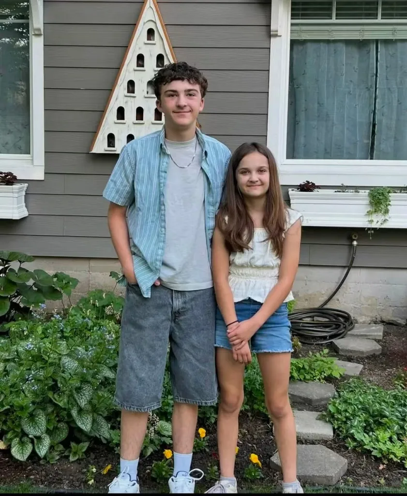 Landon Ghekiere, 15, and Charlotte Ghekiere, 12, standing side-by-side in front of a house.