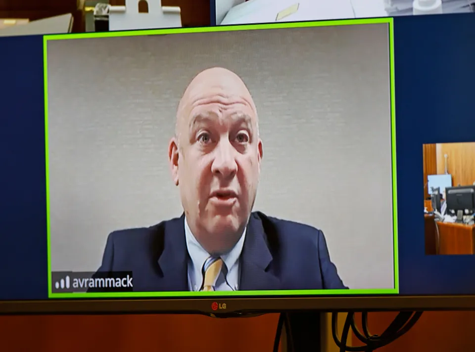 Prosecution witness Dr. Avram Mack testifying via remote video during a murder trial.