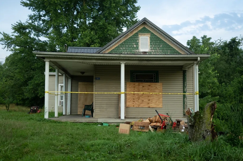 The front of 82 Ohmer St. in Hamden, Ohio, a house with boarded-up windows and crime scene tape across the porch.