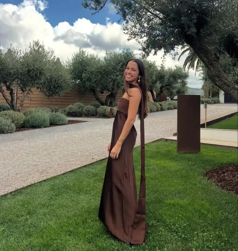 Sofia Sosa smiling while standing in a garden wearing a brown formal dress.