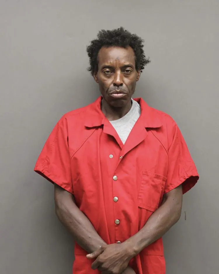A recent booking photo of a man in a red jumpsuit.