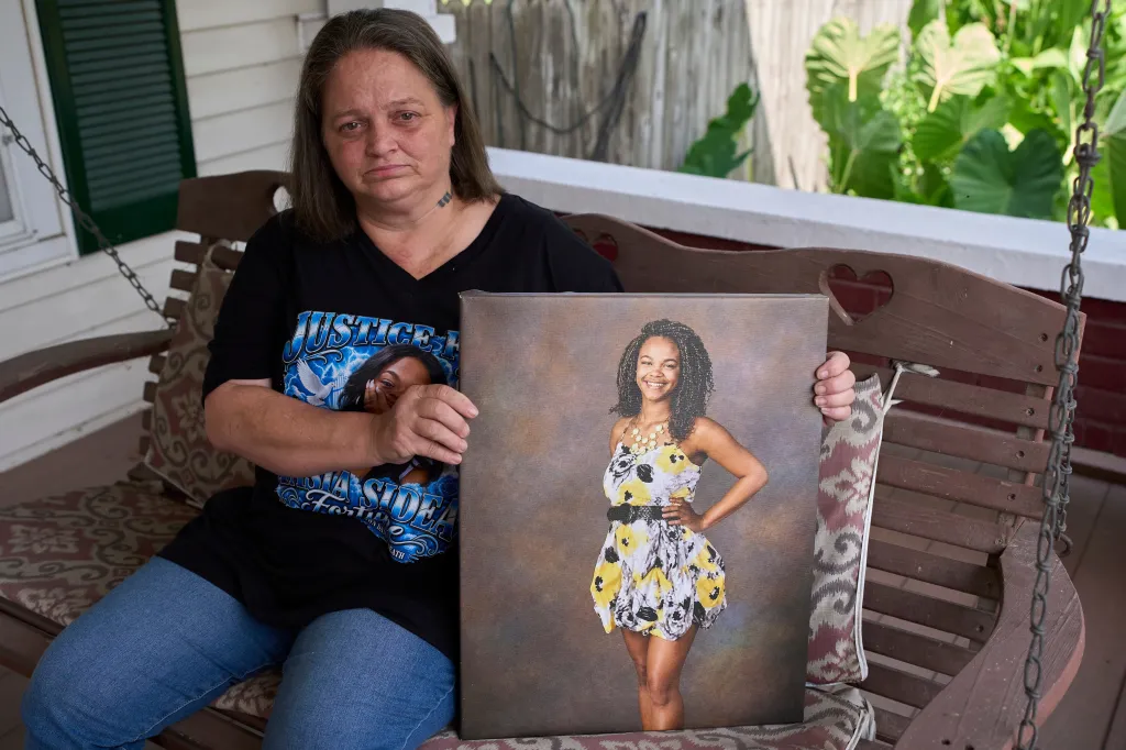 Christy Spivey holds a portrait of her late daughter, Tasia Fortune, while sitting on a porch swing.