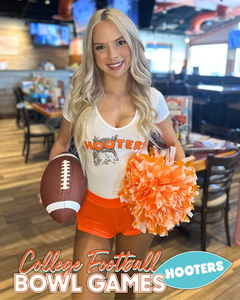 Lexi, wearing a Hooters shirt and orange shorts, holds a football and pom-pom.