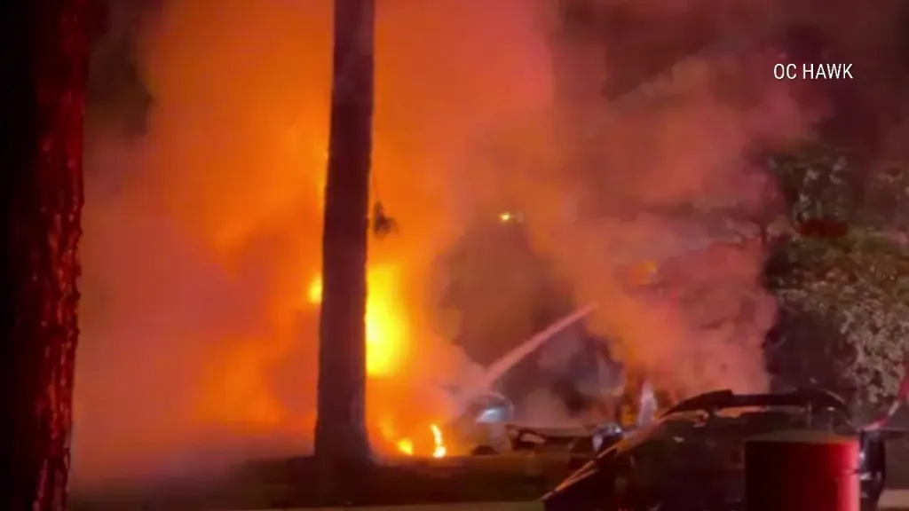 A wrecked and burning car with flames filling the night.