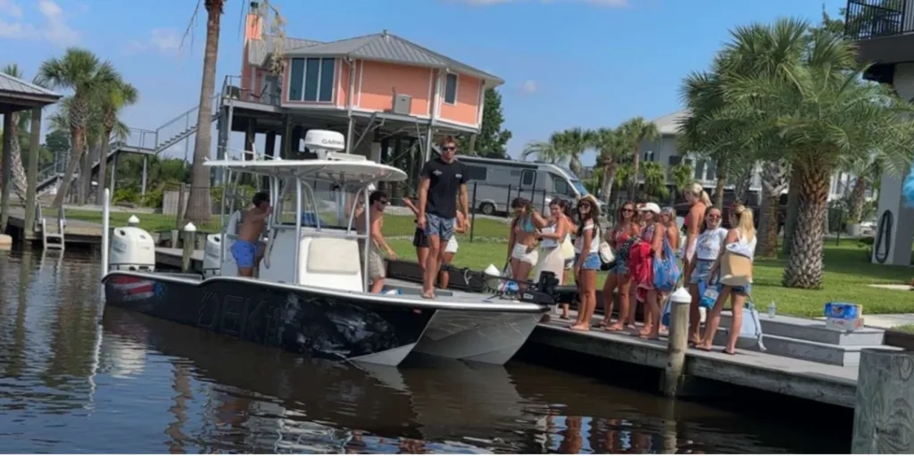 A group of friends gathering on a boat and a dock next to a canal.