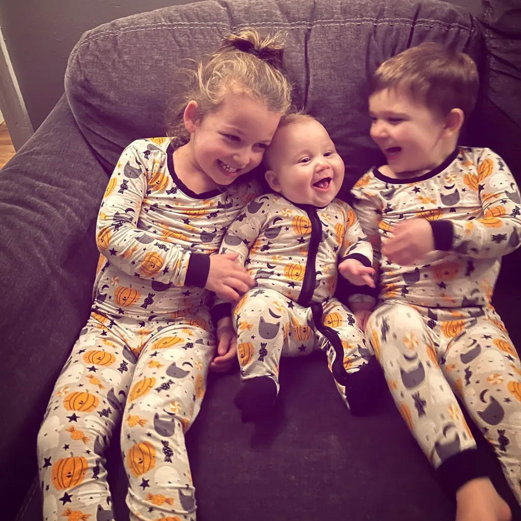 Lindsay Clancy's children Cora, Callan, and Dawson Clancy wearing Halloween-themed pajamas.