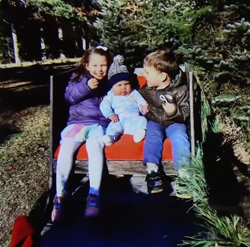 Photo of Lindsay Clancy's three children sitting together on a red sled.