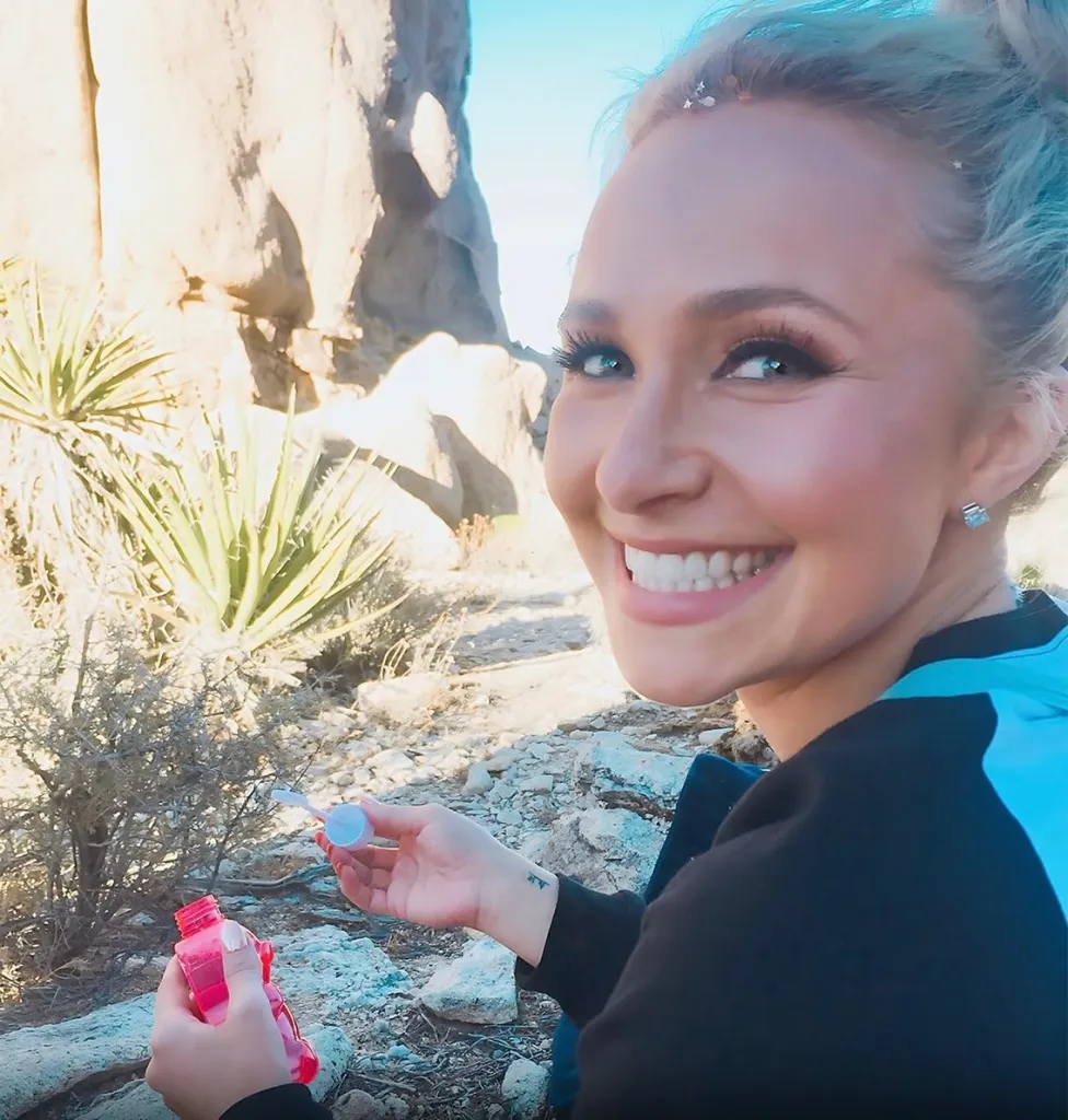 Hayden Panettiere smiling and holding a bottle of bubbles.