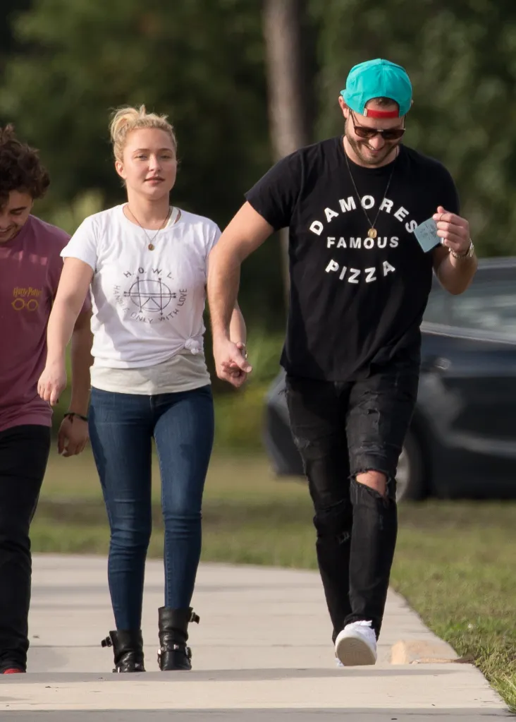 Hayden Panettiere holds hands with Brian Hickerson while walking outdoors with a third person.