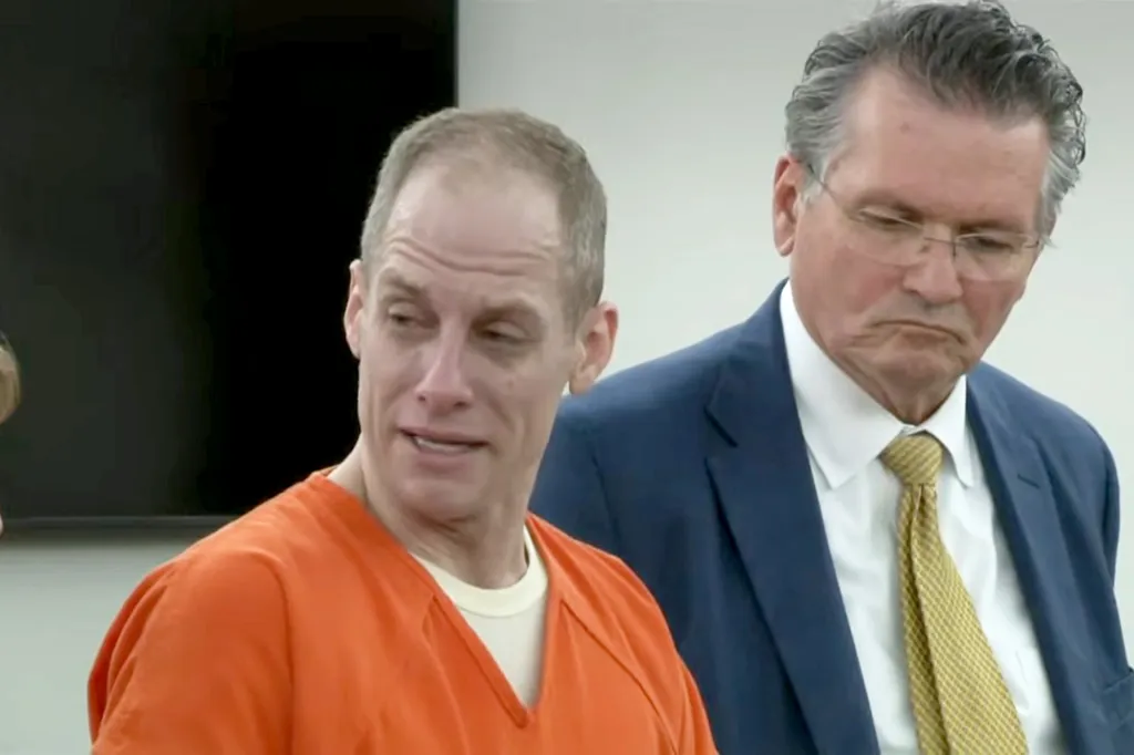 Caleb Flynn in an orange prison jumpsuit seen in court during his sentencing hearing, with his lawyer standing behind him