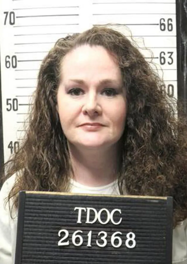 Prison mugshot of Christa Pike in front of a height chart holding a sign with her inmate number.