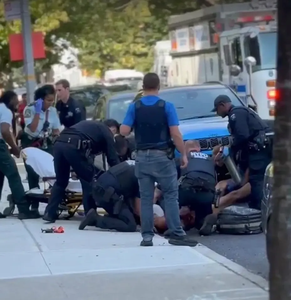 Police officers attending to an injured individual on a city street.