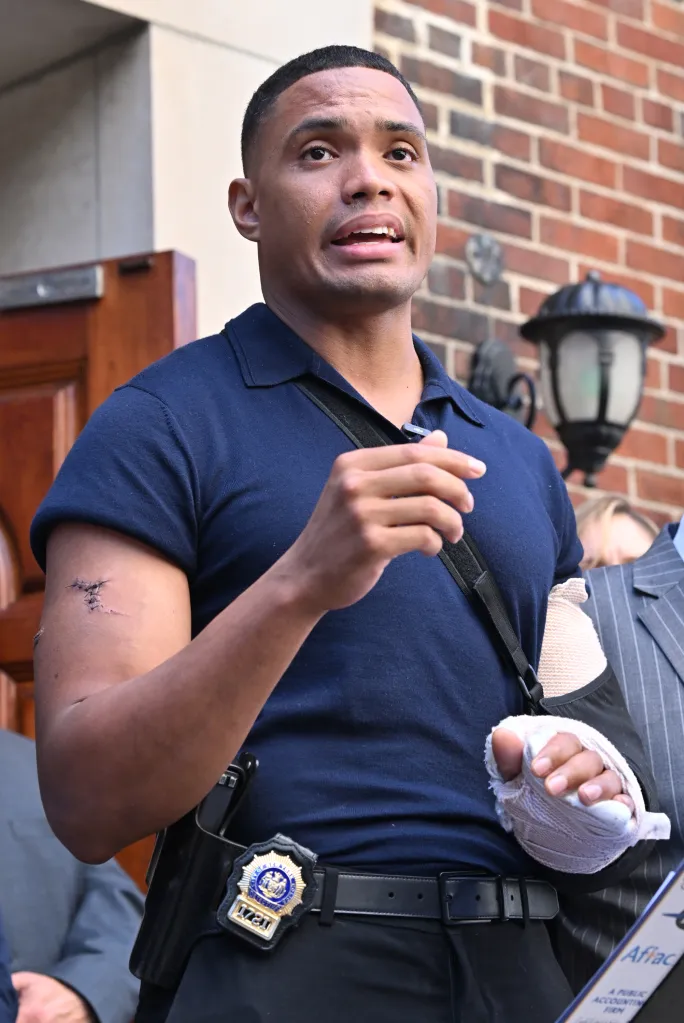 NYPD Detective Jose Mercedes speaks at a press conference with stitches visible on his right arm and his left arm in a sling following a stabbing attack.