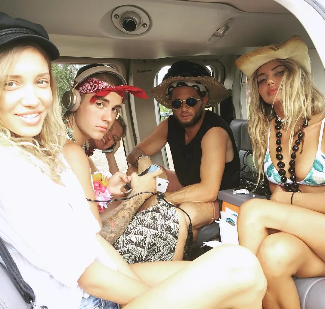 Four people pose inside a helicopter, with Justin Bieber sitting in the middle.