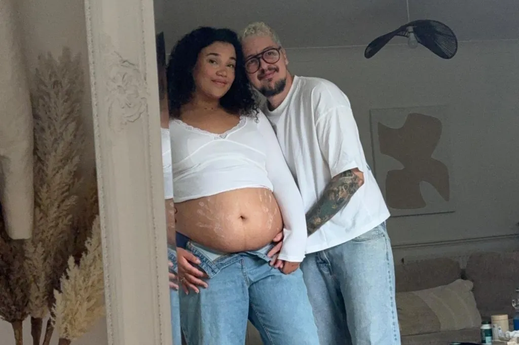 Taylor and Chloe posing in a mirror, expecting their first child.