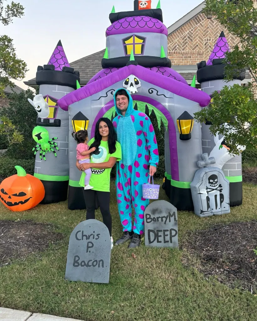 Holly Leeann Flores and Justin Hommel pose with their daughter in front of an inflatable Halloween castle.
