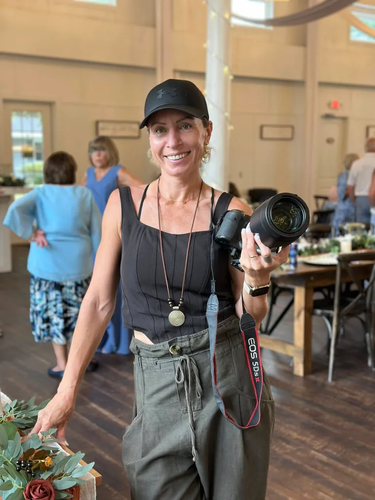 Irene Miller holding a camera in an indoor venue.