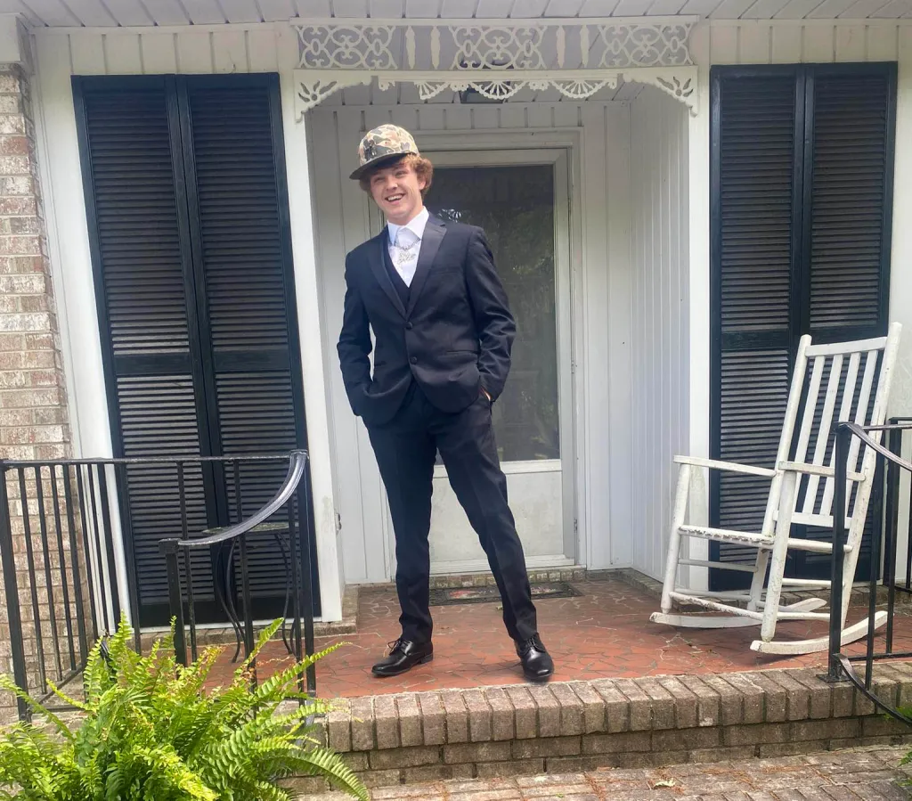 Trey Wright wearing a suit and camouflage hat on a porch.