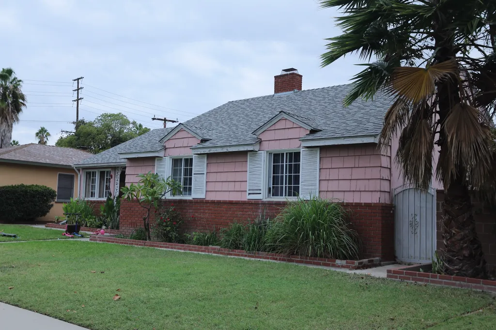 A single-story pink house with a brick base and a gray roof in Anaheim, California.