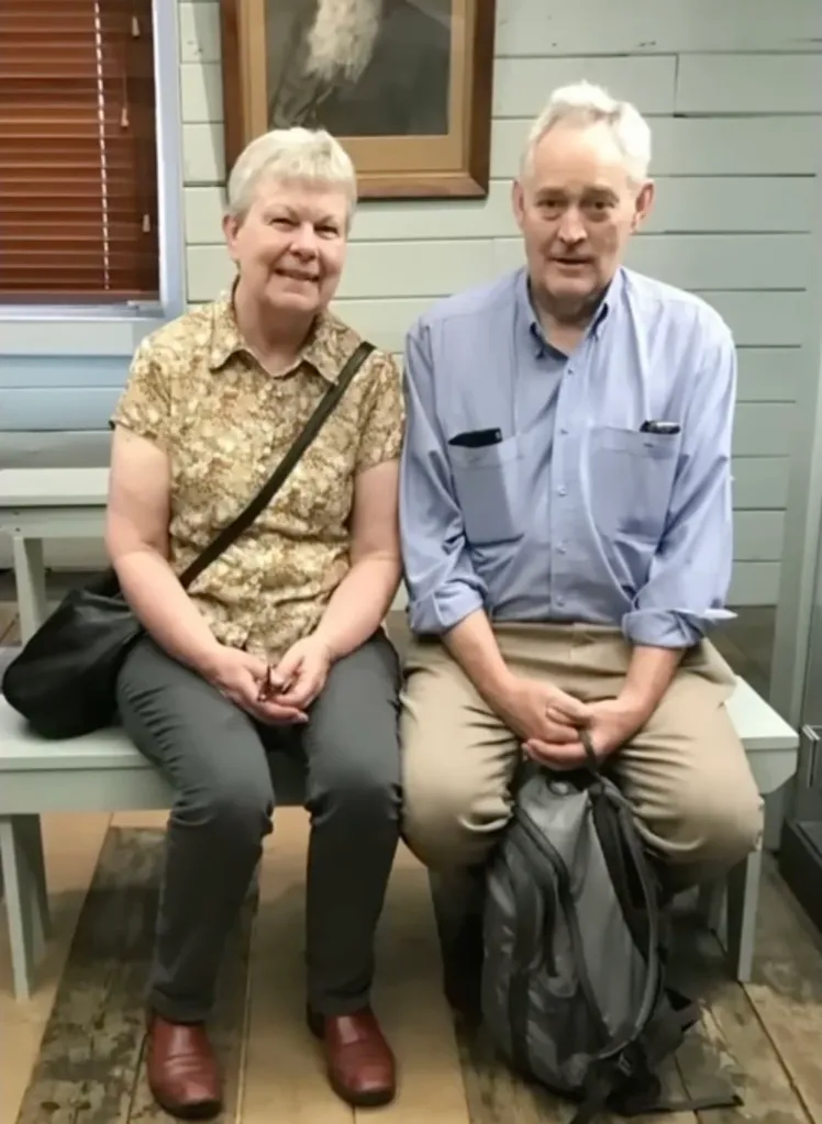 Heather and Ian Wilkinson smiling and sitting next to each other on a bench.