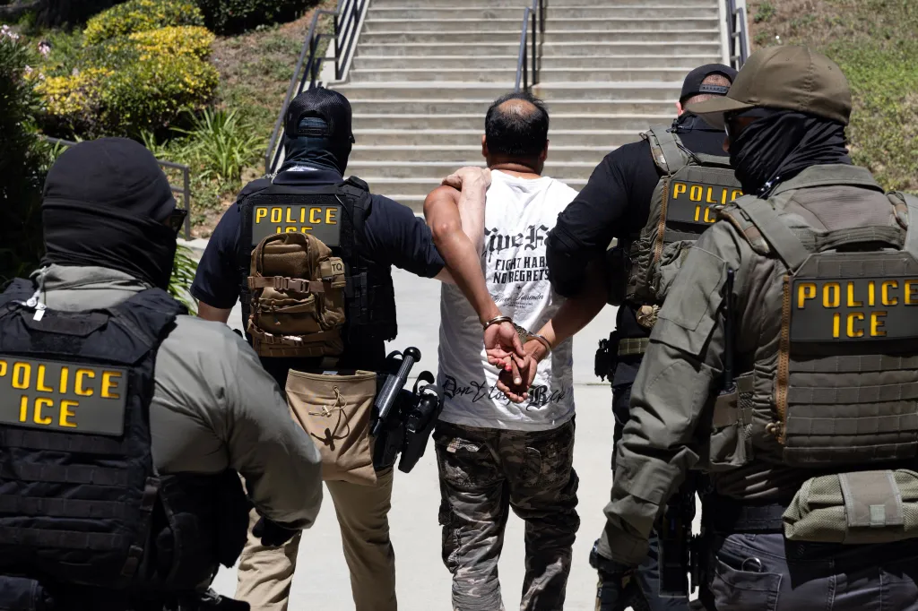 ICE agents escorting a handcuffed detainee outside the Ventura County Government Center.