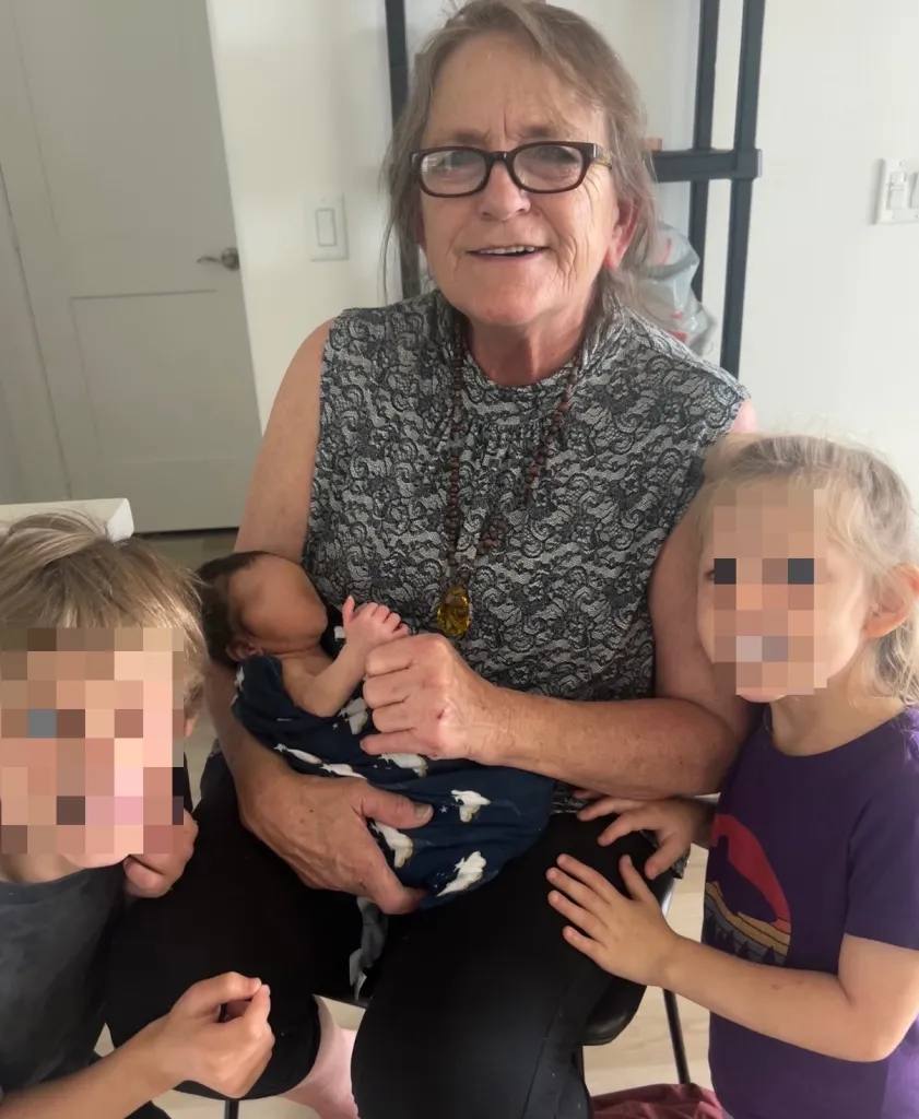 Theresa Garcia, 71, holding a baby with two children nearby.