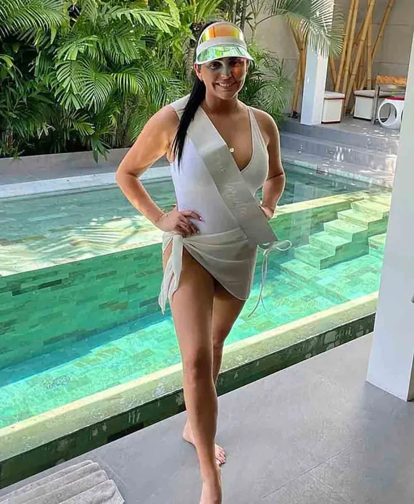 Tayla Brailey posing in a white swimsuit by a pool.