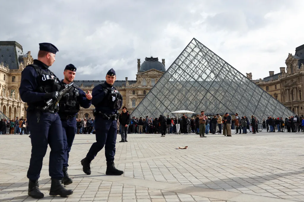 French CRS riot police officers walk near the glass Pyramid of the Louvre Museum in Paris.