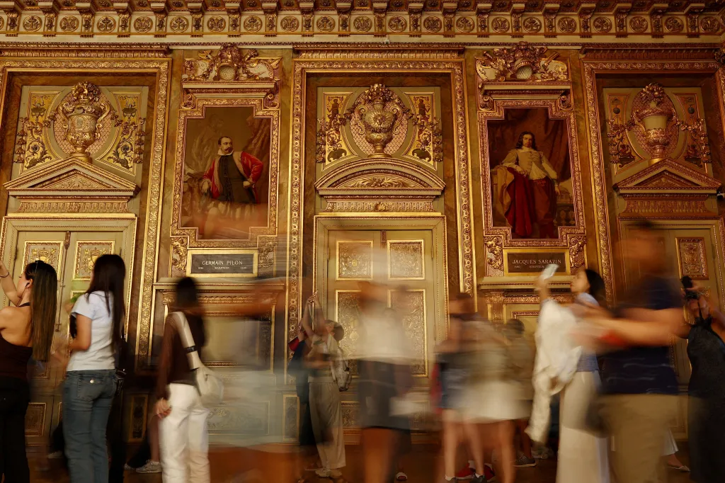 Visitors walk through the Apollo Gallery at the Louvre Museum in Paris.
