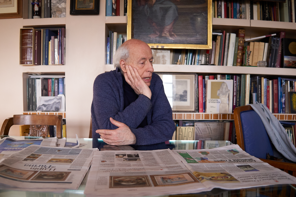 Art historian Claudio Strinati sits at a table with newspapers reporting the theft of three paintings.