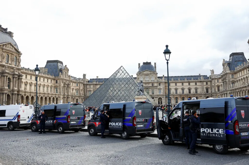 French police vans parked near the glass pyramid of the Louvre Museum.