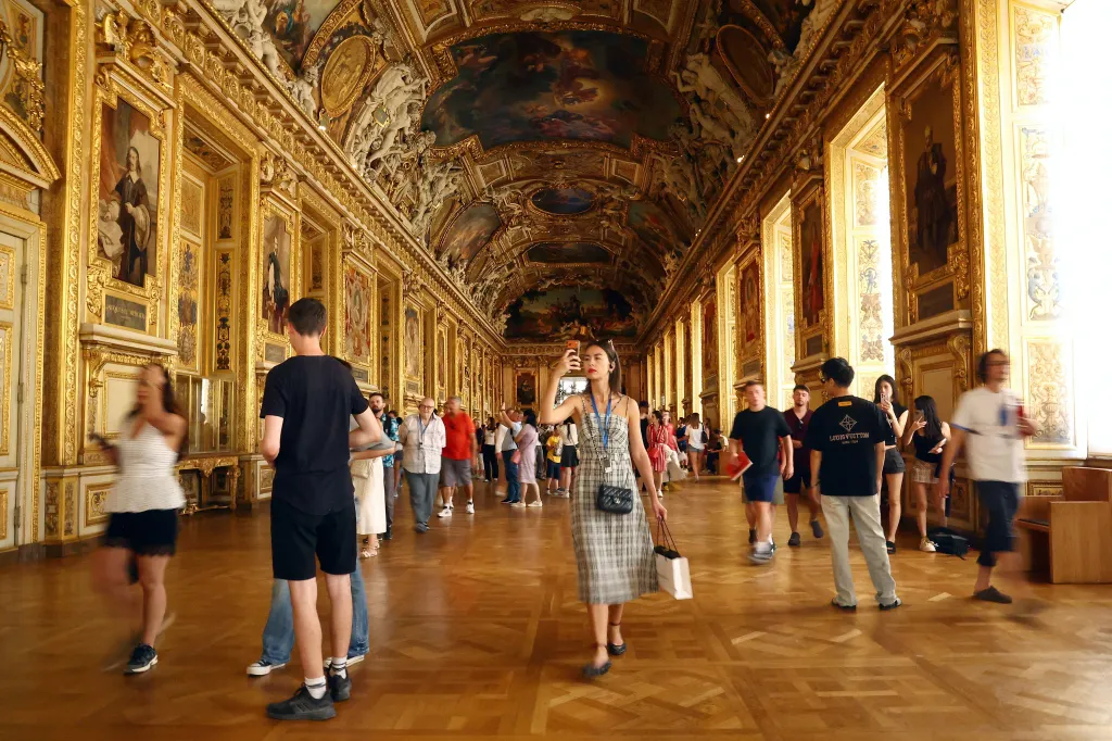 Visitors walk through the ornate Apollo Gallery at the Louvre Museum in Paris.
