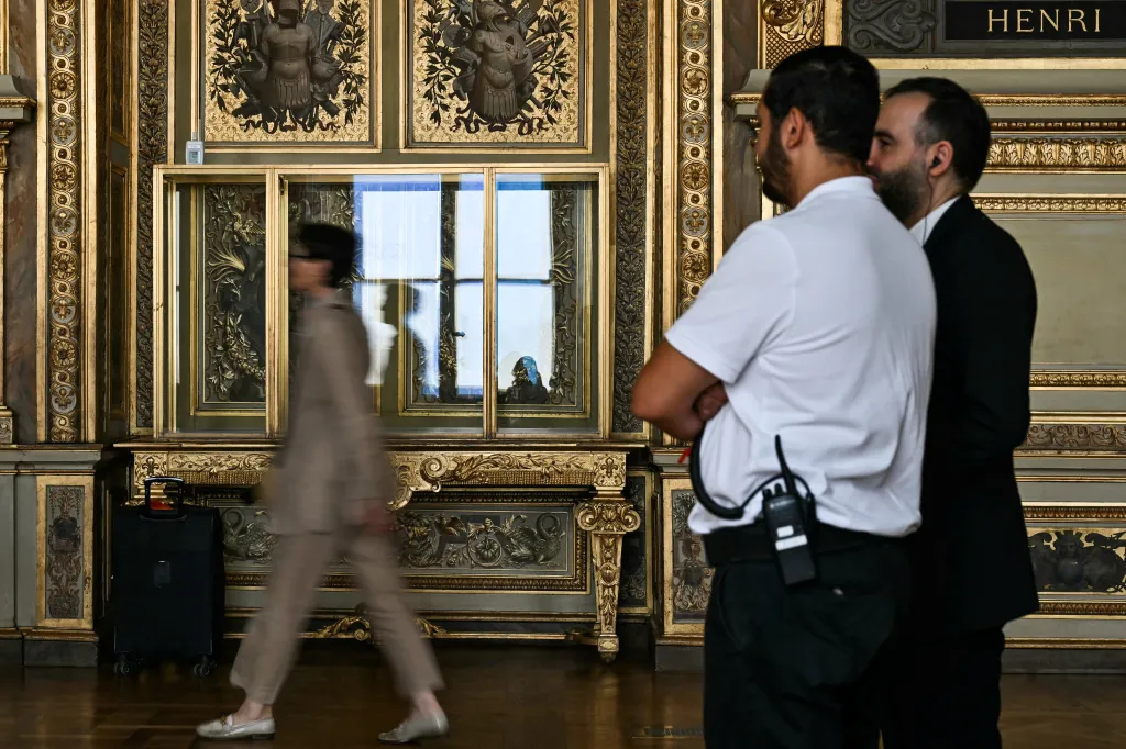 Security guards stand watch as a visitor arrives at the reopening of the Apollo Gallery at the Louvre Museum in Paris.